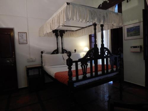 a bedroom with a bed with a canopy at WelcomHeritage Panjim Inn in Panaji