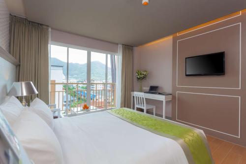 a hotel room with a bed and a large window at Best Western Patong Beach in Patong Beach