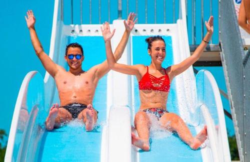 un homme et une femme sur un toboggan dans l'établissement MOBIL HOME 8 PERSONNES 2 SALLES DE BAIN 40 m2 HAUT STANDING, à Aureilhan