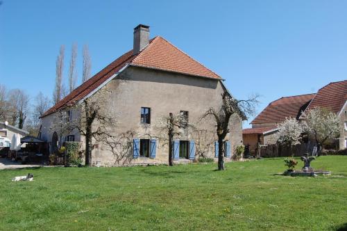 an old house in a field with a dog in front of it at Chambre d'hôtes Juste-Confortable in Fleurey-lès-Lavoncourt