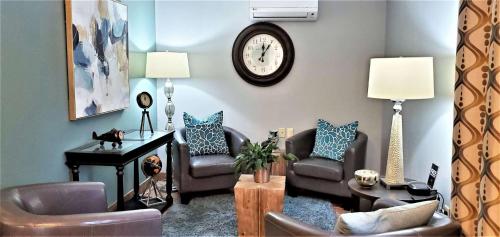 a living room with two chairs and a clock on the wall at Sonesta Simply Suites Parsippany Morris Plains in Morris Plains