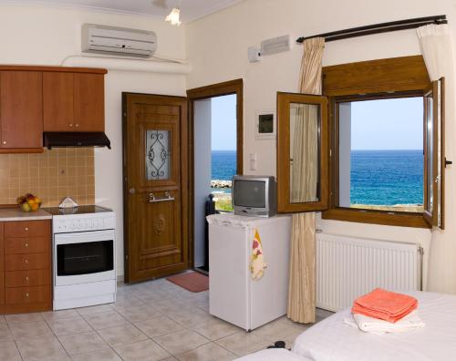 a kitchen with a refrigerator and a window with the ocean at Apartments Christina in Panormos Rethymno