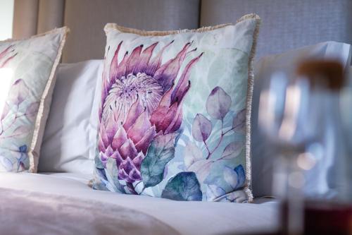 a pillow on a bed with a flower on it at Chateau de Marine Boutique Hotel in Struisbaai