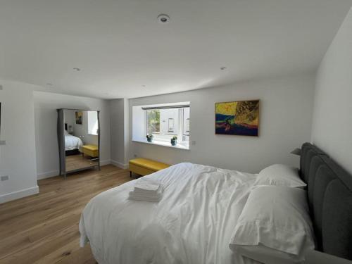 a white bedroom with a bed and a mirror at Canalside Bude in Bude