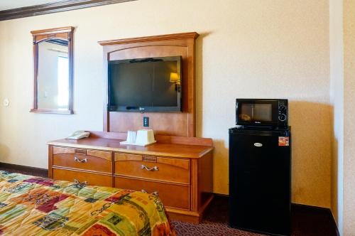 a hotel room with a bed and a dresser with a television at Touristlodge in Inglewood