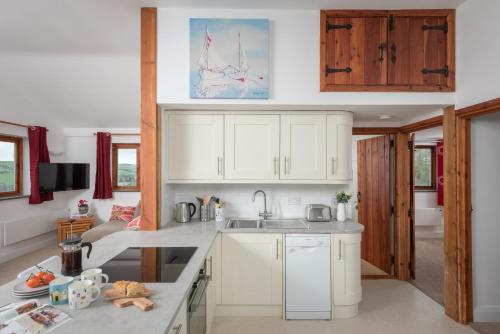 una cocina con armarios blancos y fregadero en The Hut, en Bodmin