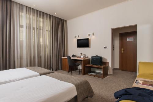 a hotel room with two beds and a desk and a television at Antique Forum Hotel "Self Check-in" Stara Zagora in Stara Zagora
