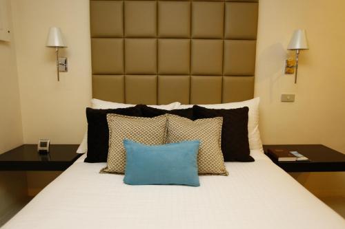 ein Schlafzimmer mit einem Bett mit einem blauen Kissen darauf in der Unterkunft Oracle Hotel and Residences in Manila