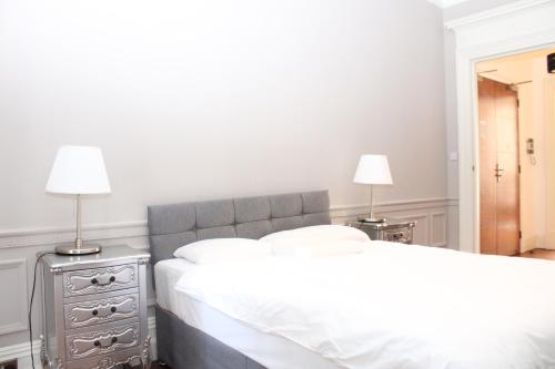 two beds in a bedroom with two lamps on tables at Sloane Square Apartments in London