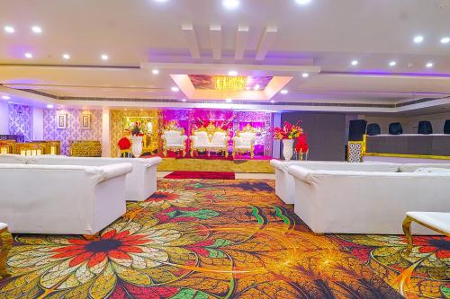 a banquet hall with white chairs and a colorful carpet at FabHotel Prime Z Grand in Ludhiana