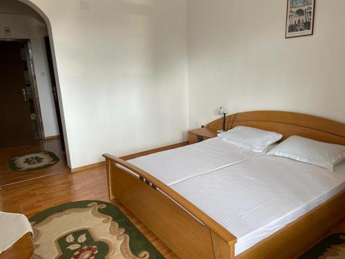 een slaapkamer met een houten bed met witte lakens bij Casa de Pelerinaj Ierusalim Hozeva in Mînăstirea Neamţ