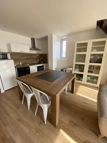 une cuisine avec une table en bois et quelques chaises dans l'établissement Le Presbytère des Baraques à Blériot-Plage - Apt 3, à Sangatte