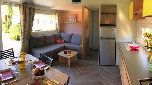 copinsdeslandes mobil home 8pers في Gastes: مطبخ وغرفة معيشة مع أريكة وطاولة
