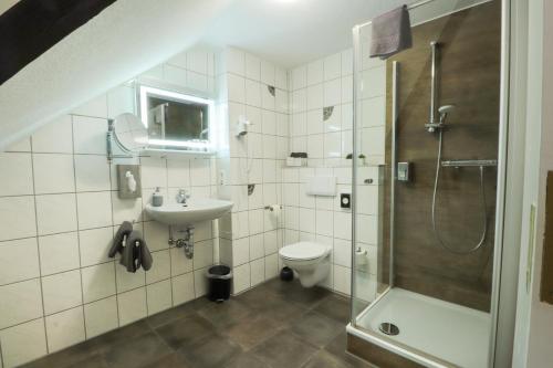 a bathroom with a shower and a toilet and a sink at Hotel Am Dalwigker Tor in Korbach