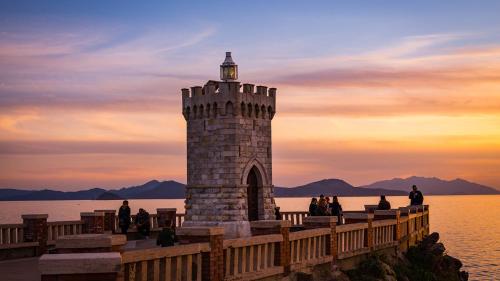 un faro al final de un muelle con puesta de sol en Albergo Italia, en Piombino