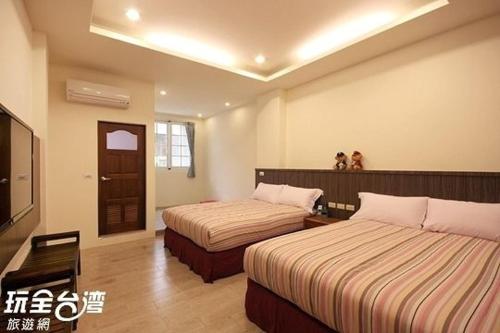 a hotel room with two beds and a television at Kenting Lian Nan Wan in Nanwan