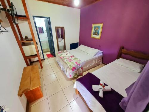 1 dormitorio con 2 camas y pared púrpura en Pousada Canto Nosso en São Pedro da Serra