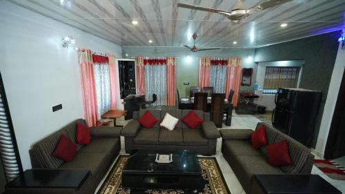 a living room with a couch and red pillows at Srinikethana Home Stay with Swimming Pool in Madikeri