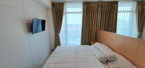 a bedroom with a bed with a television and a window at TreeParkCity apartments by WinsHome in Tangerang