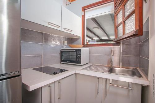 a small kitchen with a sink and a microwave at Appartement Maëva, Idéal Couple, Jacuzzi in Quartier Monplaisir