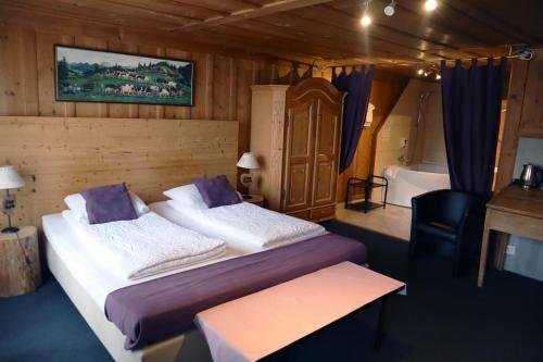 una camera con letto e vasca da bagno, un letto e una scrivania di Gruyère Rooms a Gruyères