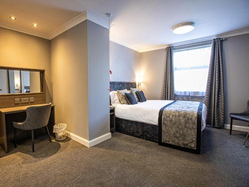 a hotel room with a bed and a desk and a mirror at Sure Hotel by Best Western Lockerbie in Lockerbie