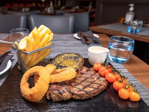 a table with steak and french fries and a basket of onion rings at Sure Hotel by Best Western Lockerbie in Lockerbie