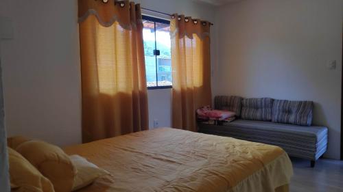 ein Schlafzimmer mit einem Bett und einem Stuhl und einem Fenster in der Unterkunft Flat com portão na Praia in Angra dos Reis