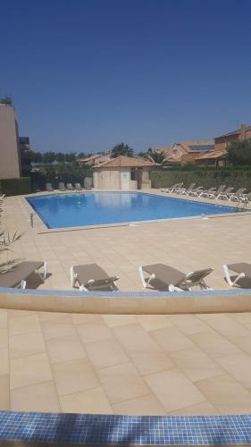 un groupe de chaises longues et une piscine dans l'établissement LES EMBRUNS - SPACIEUX APPARTEMENT AVEC PISCINE - wifi- parking, à Saint-Cyprien