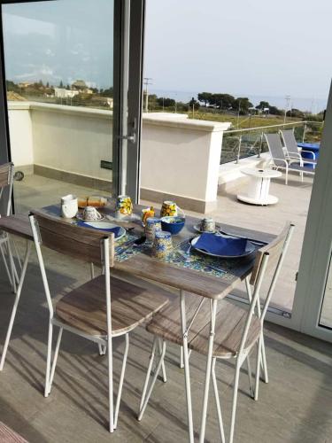 a dining table and chairs with a view of the ocean at B&B Torre Pozzillo in Cinisi