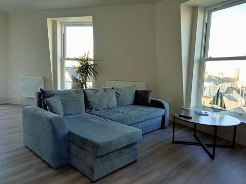 a living room with a blue couch and a table at Glorious Duplex Holiday Apartment By The Sea in Bognor Regis