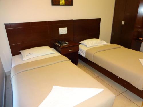 two beds in a hotel room withermottermottermott at Hotel Sky Lite in Coimbatore