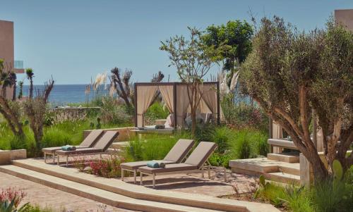 two lounge chairs in a garden with the ocean in the background at Fairmont Taghazout Bay in Taghazout