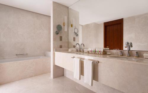 a white bathroom with two sinks and a tub and a bath tubermott at Swissôtel Wellness Resort Alatau Almaty in Almaty