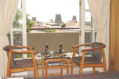 a dining room table with two chairs and a table with drinks at Hotel Supreme in Madurai
