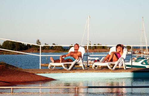 two men and a woman sitting in lawn chairs on a dock at Best Western Hotel Corallen in Oskarshamn