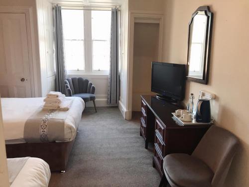 um quarto de hotel com duas camas e uma televisão de ecrã plano em Alexander Guest House em Edinburgo