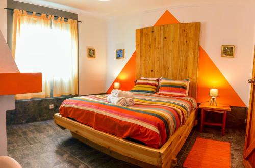 a bedroom with a large bed with an orange headboard at Sea Roots "Sea Zone" in Mosteiros