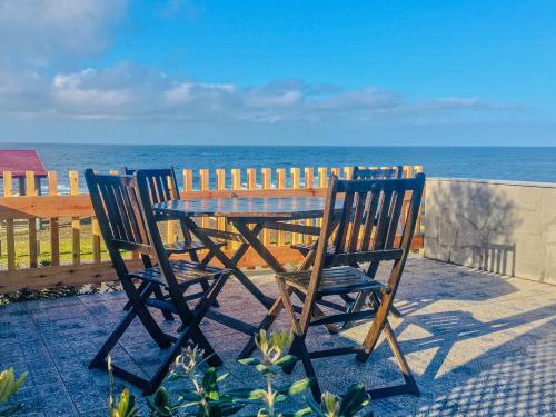 two chairs and a wooden table on a balcony with the ocean at Sea Roots "Sea Zone" in Mosteiros