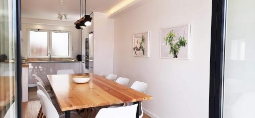 a dining room with a wooden table and white chairs at CASA TACOARIA in Fontainhas