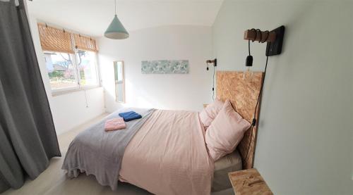 Schlafzimmer mit einem Bett mit rosa Bettwäsche und einem Fenster in der Unterkunft LA PIERRINA - Marmotte - Appart 3 étoiles in Aix-les-Bains