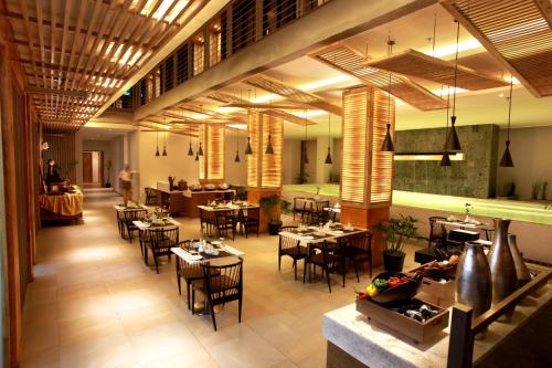 Liberta Hotel Jimbaran في جيمباران: مطعم فيه طاولات وكراسي في الغرفة