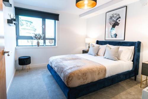 een slaapkamer met een groot bed met een blauw frame bij The Lusso Suite - 2BR - A 5* Escape Like No Other in Glasgow