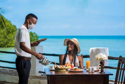 Un homme sert une femme à une table dans l'établissement Zanzibar Beach Resort, à Zanzibar City