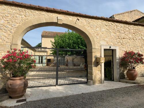 - l'entrée d'un bâtiment en pierre avec un portail et des fleurs dans l'établissement Mas de la Riale, à Gajan