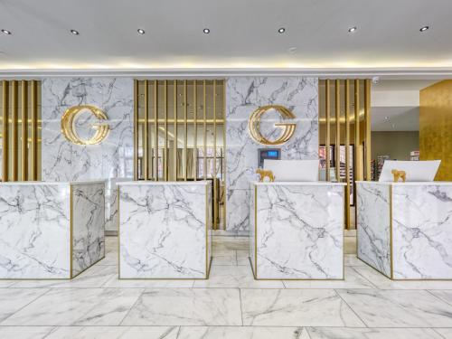 a lobby with marble walls and gold chandeliers at Triple G Hotels in Amsterdam