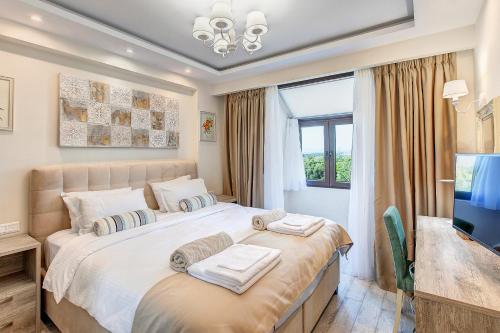 ein Schlafzimmer mit einem großen Bett und einem TV in der Unterkunft Anemone Villa, Sani Luxury Villas collection in Sani Beach