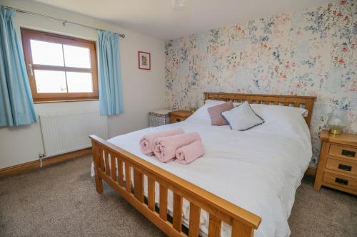 a bedroom with a bed with pink towels on it at Bramblewood Cottage 