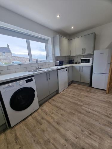 a kitchen with a washer and a sink and a dishwasher at Fairway View Cottage in Rothbury