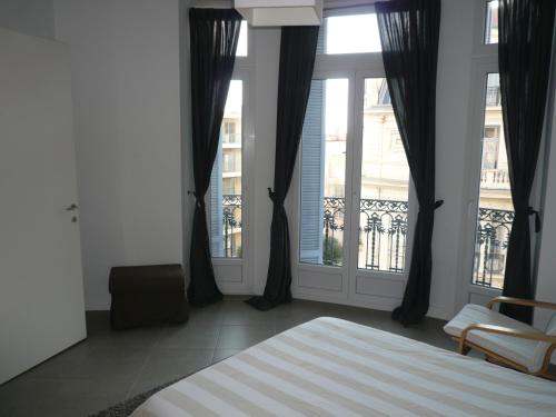 une chambre avec un lit et deux grandes fenêtres dans l'établissement 2 pièces, Centre Ville, 50 mètres plages et mer., à Menton